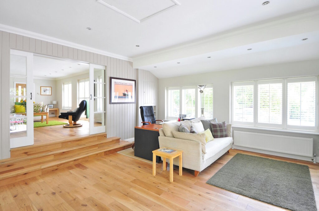 Bright living room with a white couch on black area rug, showcasing polished hardwood floors